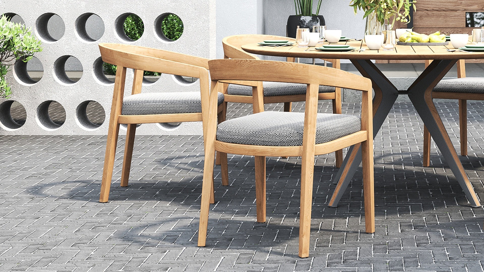 Outdoor dining set on a brick patio, with a round table & outdoor dining chairs with gray cushions.