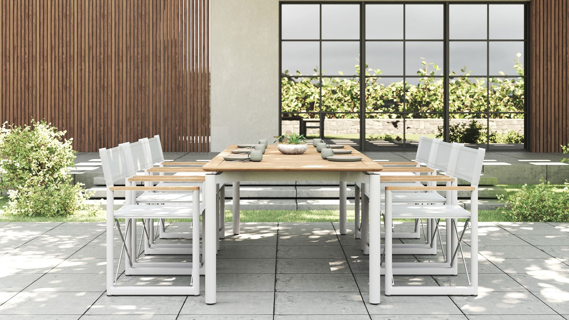Full outdoor dining set with a premium teak table and six Aleta director chairs with white frames.