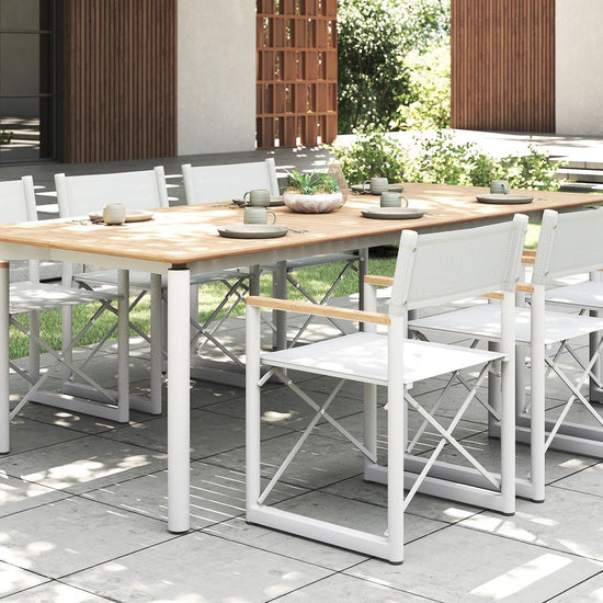Modern outdoor dining set with a teak table and eight white Aleta director chairs by Be A Little.