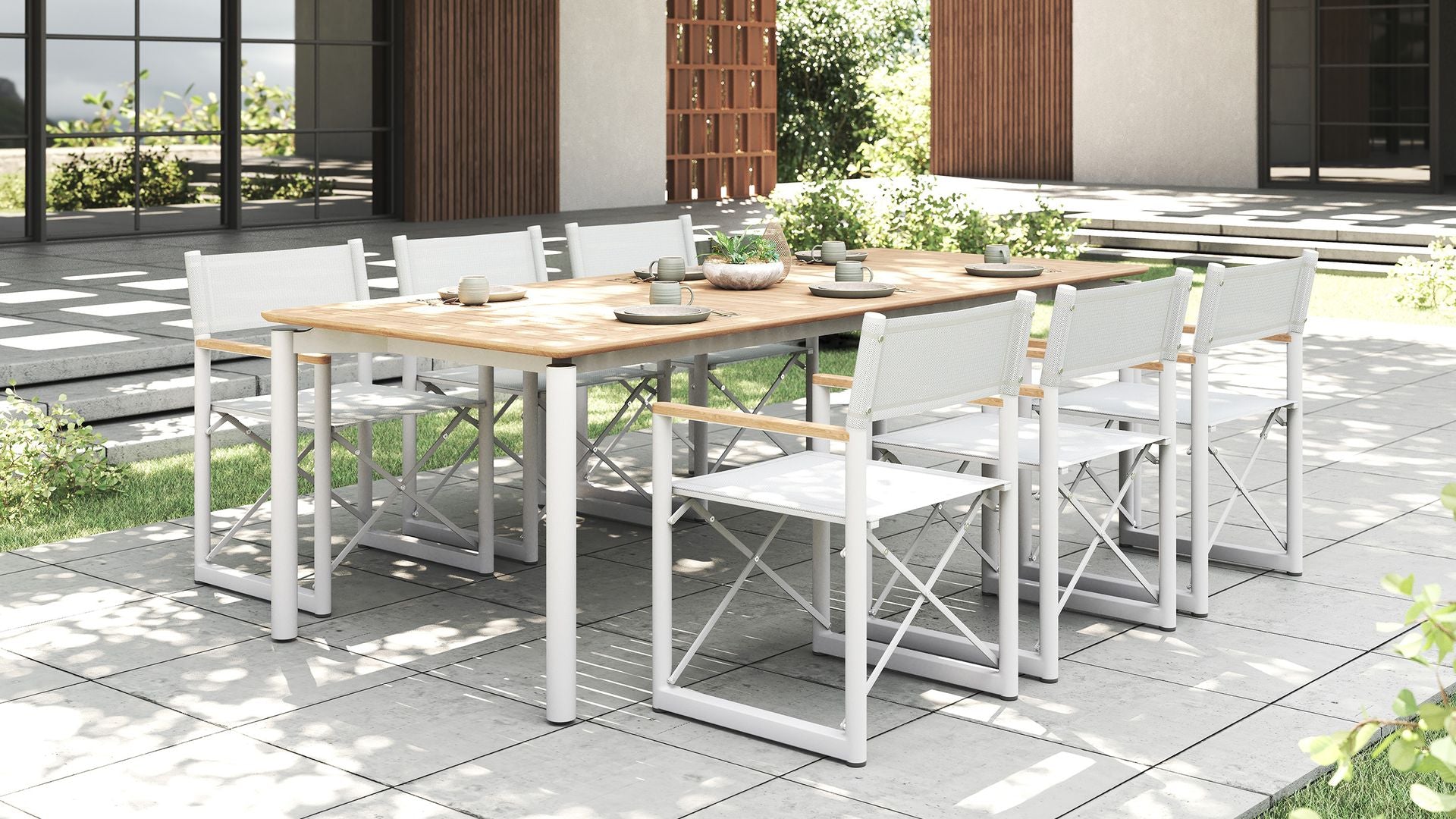 Modern outdoor dining set with a teak table and eight white Aleta director chairs by Be A Little.