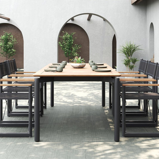A full outdoor dining set with a teak table and eight black Aleta director chairs by Be A Little.