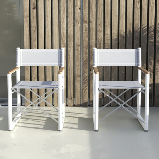 Two white Aleta director chairs with gray fabric and teak armrests, against a slatted wood wall.