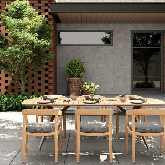 Outdoor dining set with a rectangular table & six Vento dining chairs with gray cushions on a patio.