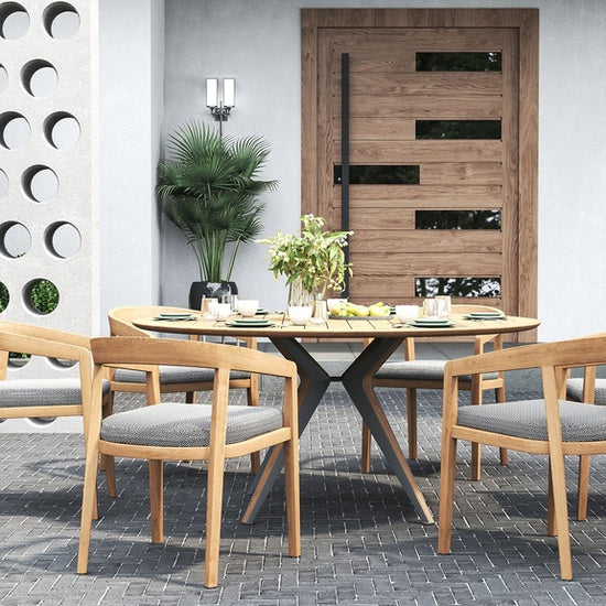 Outdoor dining set with a round table and 4 outdoor dining chairs on a patio with a perforated wall.