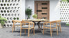 Outdoor dining set with a round table and 4 outdoor dining chairs on a patio with a perforated wall.
