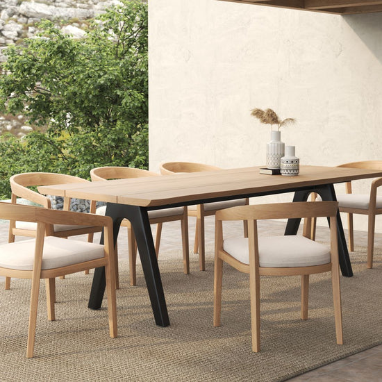 Minimalist outdoor dining set with a long wooden table, black legs, and six matching dining chairs.