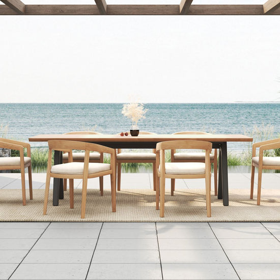 Outdoor dining set on a tiled patio overlooking the ocean, with a long table and six dining chairs.