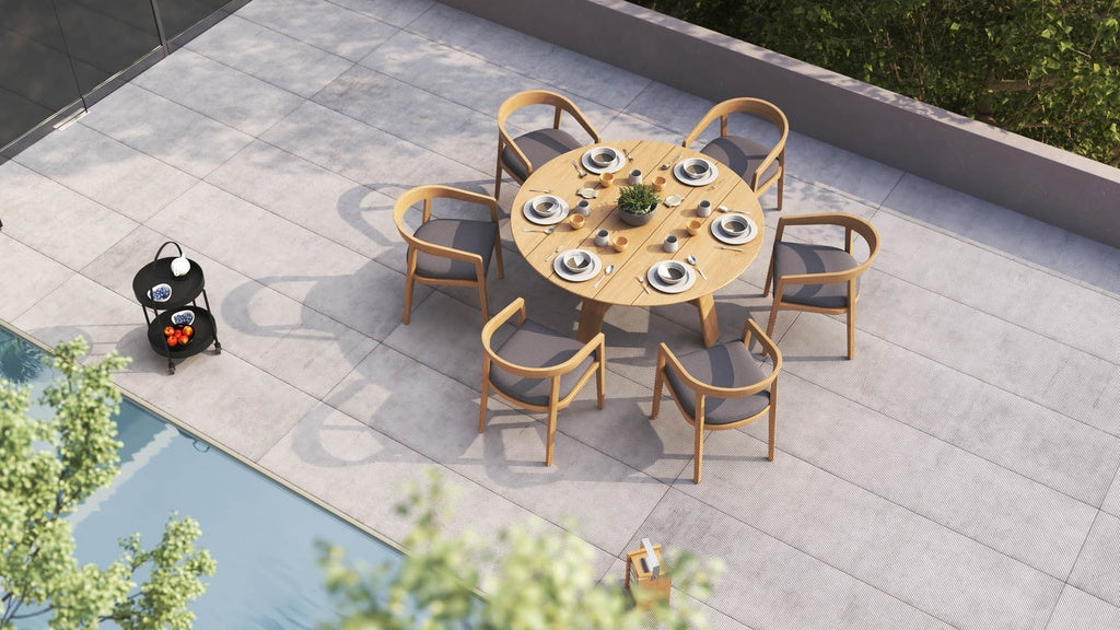 Overhead view of a round outdoor set with 6 dining chairs, & a small serving trolley nearby a pool.