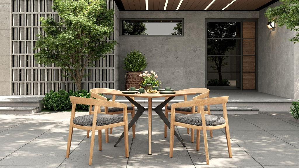 Outdoor dining set on a tiled patio, with a round wooden table & 4 dining chairs with gray cushions.