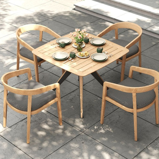 Overhead view of a square outdoor dining table with four dining chairs and gray cushions on a patio.