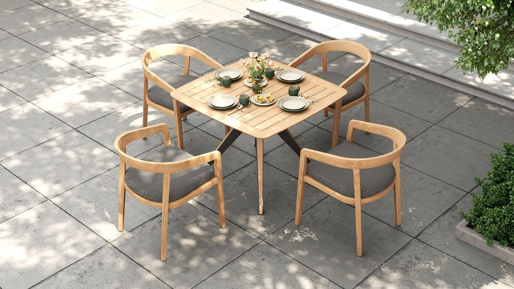Overhead view of a square outdoor dining table with four dining chairs and gray cushions on a patio.
