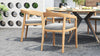 Outdoor dining set on a brick patio, with a round table & outdoor dining chairs with gray cushions.