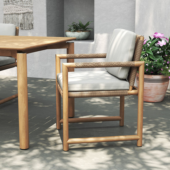 Timo dining armchair with cushions and rope detail, styled outdoors beside a wooden teak table.