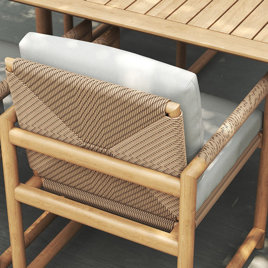 Close-up of Timo dining armchairs with rope-wrapped backrest and light cushions at a wooden table.