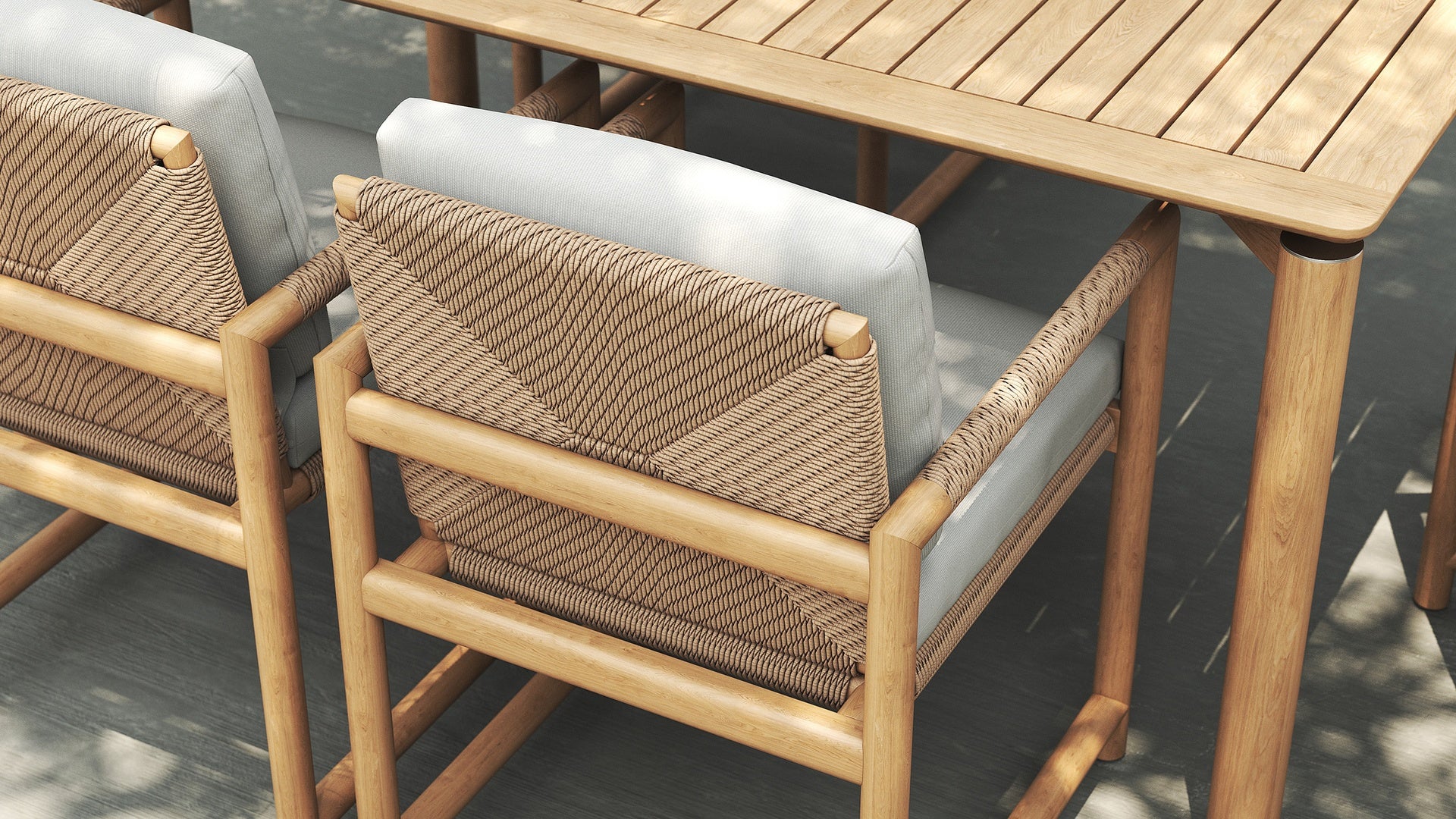 Close-up of Timo dining armchairs with rope-wrapped backrest and light cushions at a wooden table.