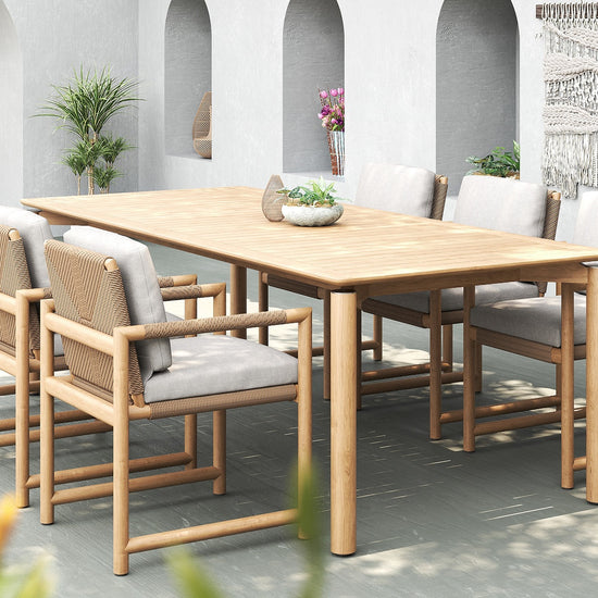 Outdoor dining setup with Timo dining armchairs and a wooden teak table in a modern patio setting.