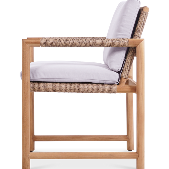 Side view of the Timo dining armchair with premium teak wood frame, rope details, & white cushions.